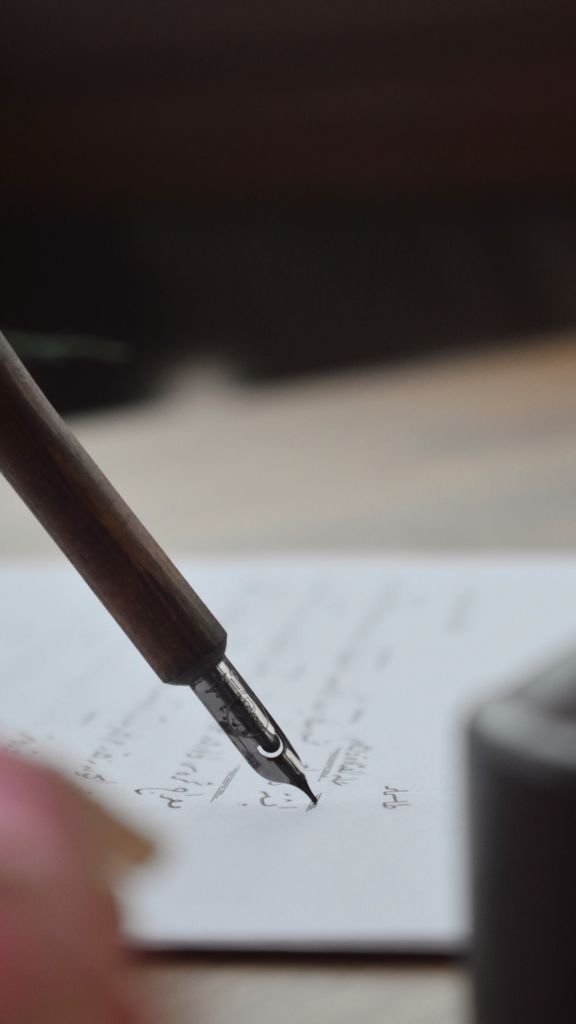 A detailed shot of a fountain pen writing elegant cursive script on paper.