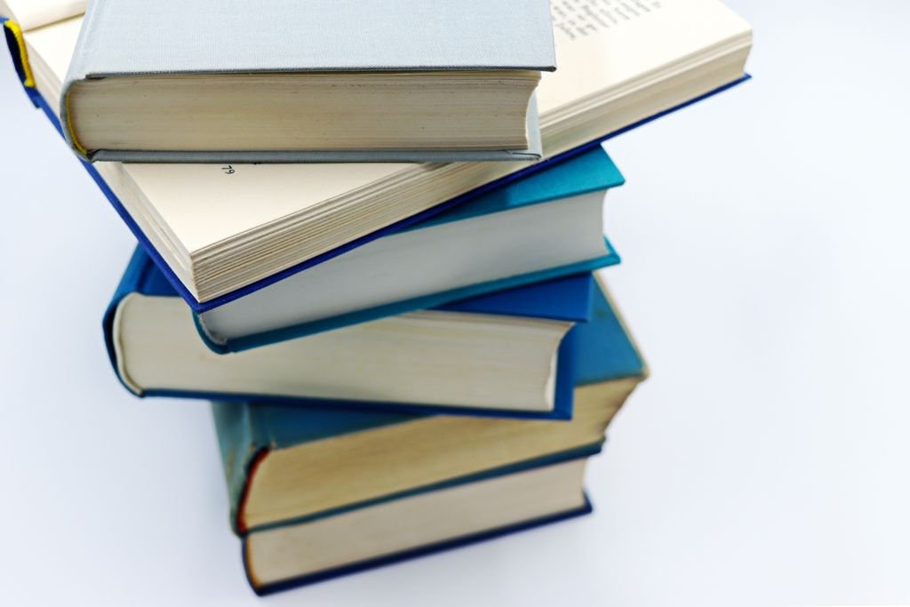 A pile of books with blue covers on a white background, symbolizing education and knowledge.